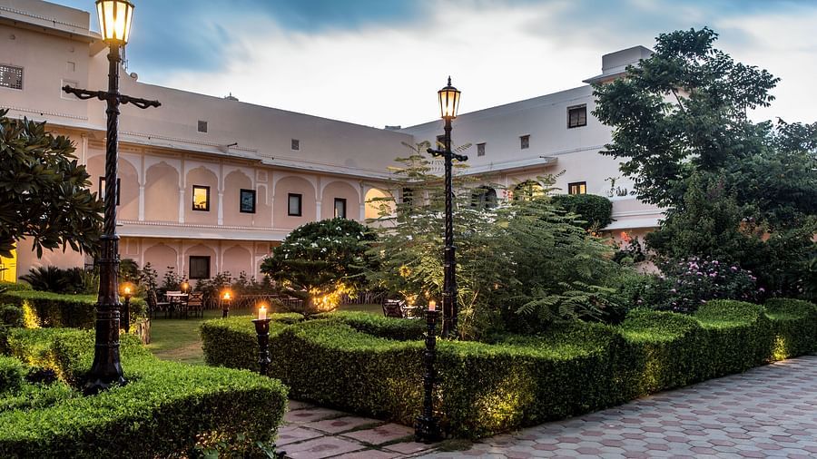 An exterior view of Royal Heritage Haveli at dusk with illuminated pathways and landscaped gardens.