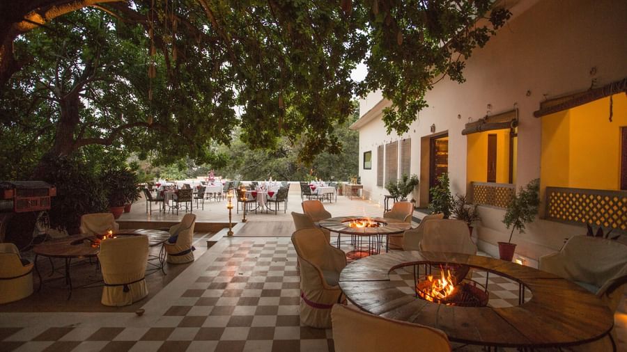 An outdoor patio or courtyard at Royal Heritage Haveli with tables and chairs, illuminated by lights, and a checked floor pattern.