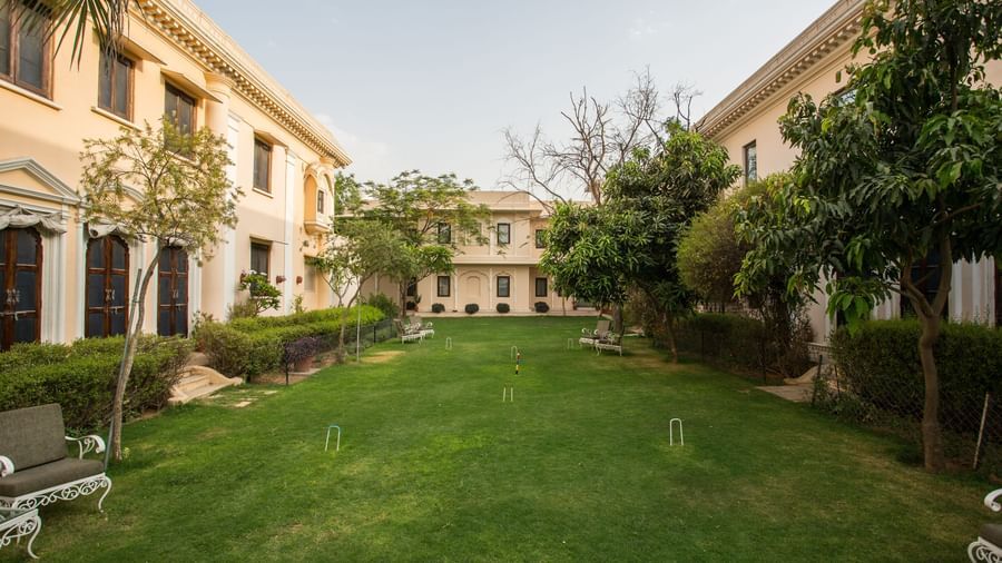 A well-maintained lawn with a building of Royal Heritage Haveli in the background under a clear sky.