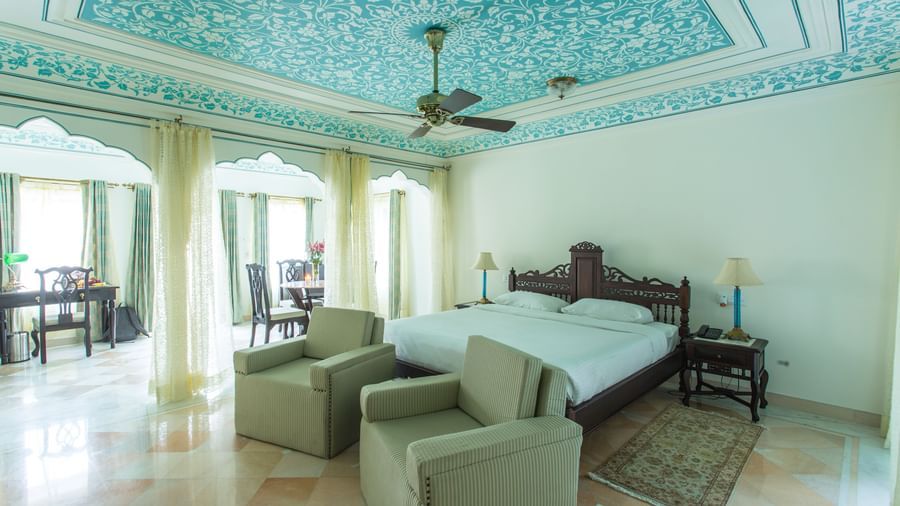 A spacious room at Royal Heritage Haveli with blue patterned ceilings, a seating area, and large windows.