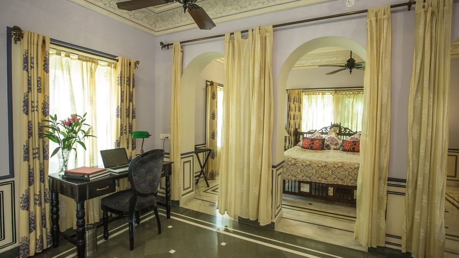 A room at Royal Heritage Haveli with a desk area in the foreground and a view into a connected bedroom through an archway.