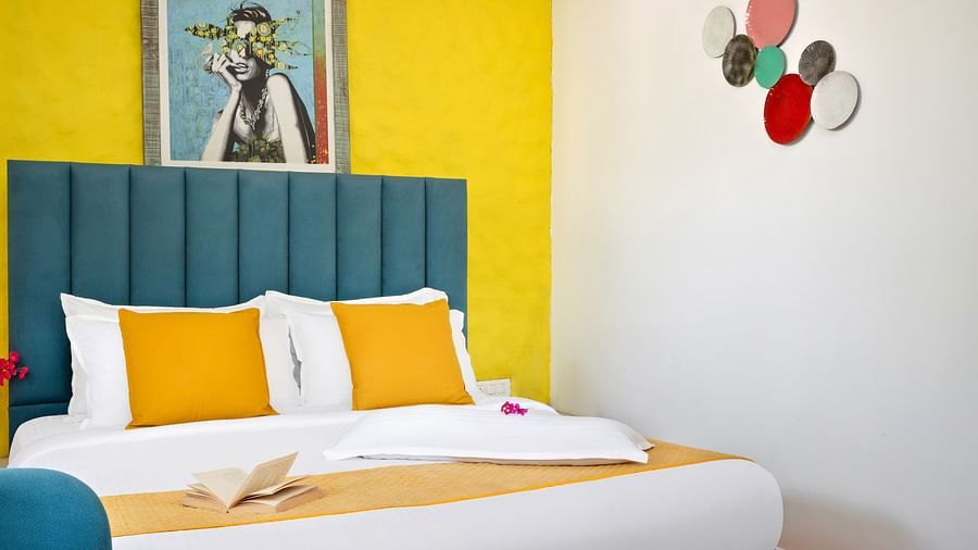 Bright bedroom featuring a wall, a plush teal headboard, and colourful cushions.