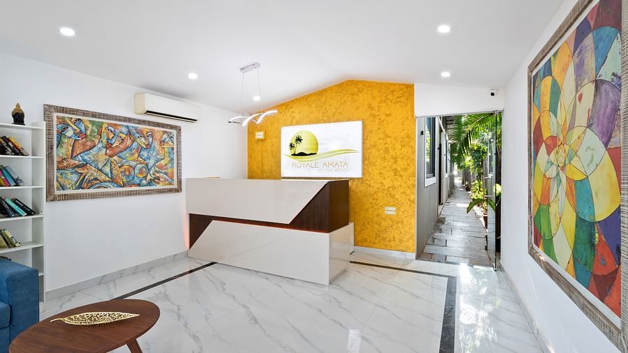 A bright reception area with a mix of white and yellow walls, colourful paintings, and a sleek modern desk.