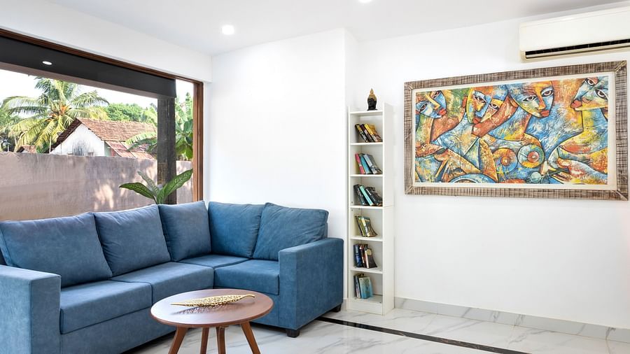 A spacious living room featuring a sectional sofa, a wooden coffee table, and vibrant artwork displayed on the wall.