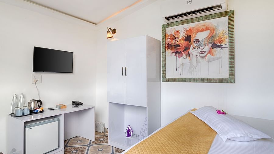  A cozy bedroom with a bed, side table, and artwork on the wall.