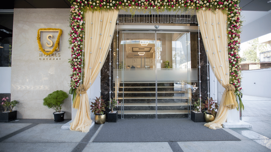 A large glass door entrance is decorated with a floral archway at S Hotels, in T. Nagar, Chennai.
