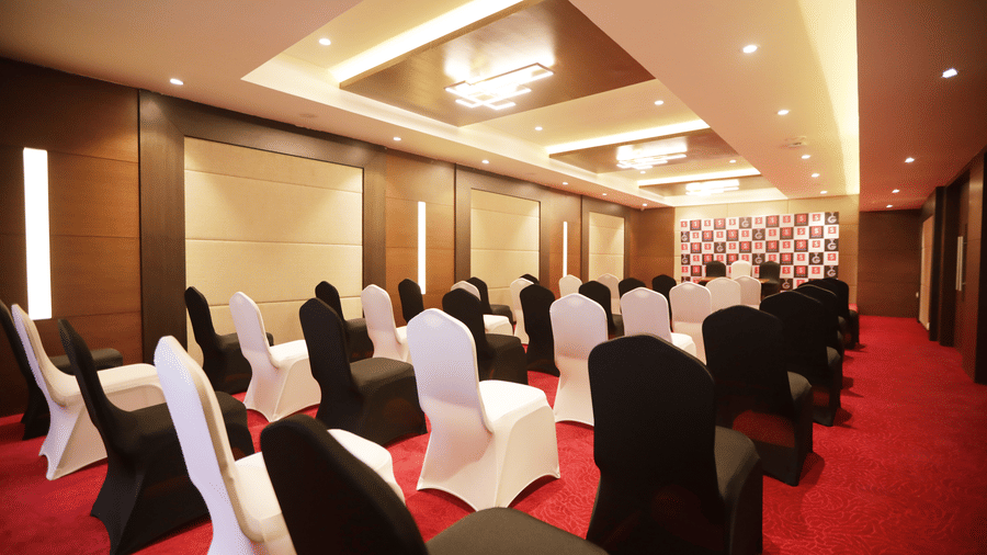 Rows of chairs covered in black and white fabric over a bright red carpet at S Hotels, Chennai.