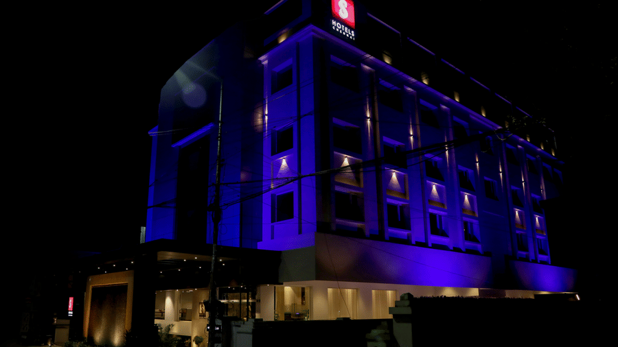 A large modern multi storey hotel building is lit up with lights against the night sky at S Hotels, Chennai.