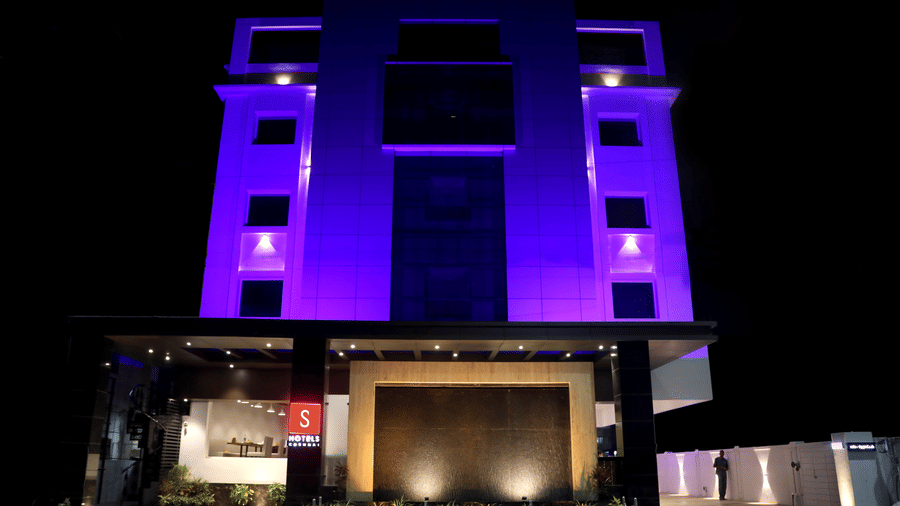 A large modern multi storey hotel building is lit up with lights against the night sky at S Hotels, Chennai.