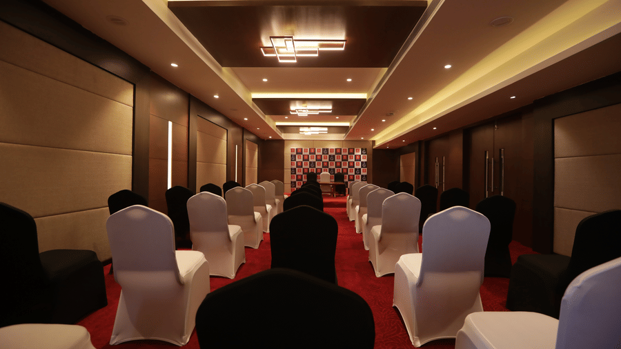 The Venus hall at S Hotels, Chennai, set up for an event with many rows of chairs covered in dual-coloured fabric facing forward.
