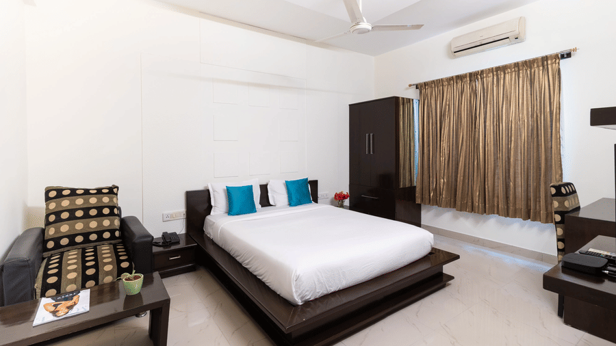 Superior room with double bed, teal pillows and air conditioning at Sanctum Suites Domlur Bangalore