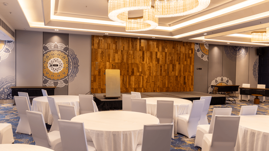 Event hall featuring 1 speaker's podium and a decorative wooden backdrop at Sands Point Hotel, Pondicherry.