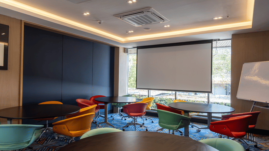 Round dark wood tables and 2 abstract framed prints at Sands Point Hotel, Pondicherry.