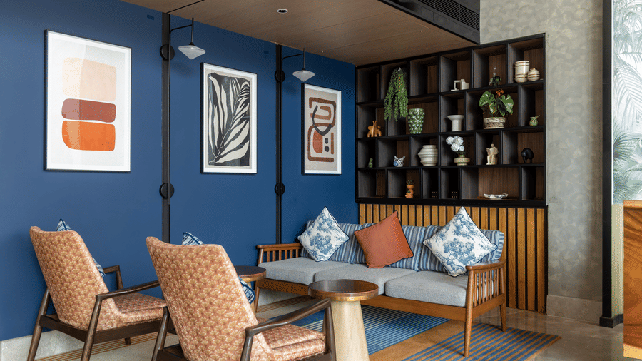 A blue accent wall featuring 3 framed pictures and 1 wooden display shelf at Sands Point Hotel, Pondicherry.