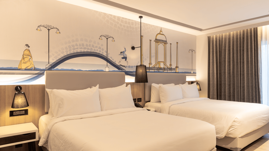 Interiors of the Sands Point Hotel, Pondicherry, Family Room showing 2 beds with white linen, light grey headboards with warm lighting, built-in wooden bedside panels.