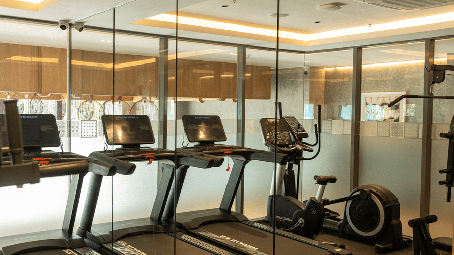 Gym facility equipped with 3 modern treadmills and floor-to-ceiling mirrors at Sands Point Hotel, Pondicherry.