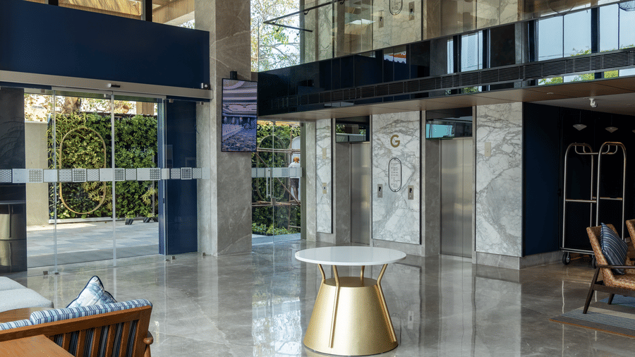 Polished marble foyer with 1 gold-based side table near the lift lobby at Sands Point Hotel, Pondicherry.