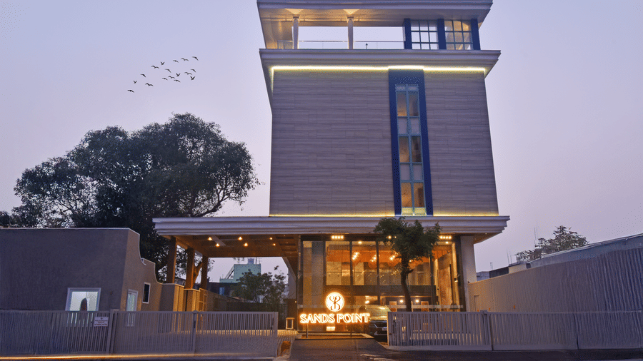 A wide view of the modern hotel exterior against a purple dusk sky at Sands Point Hotel, Pondicherry.