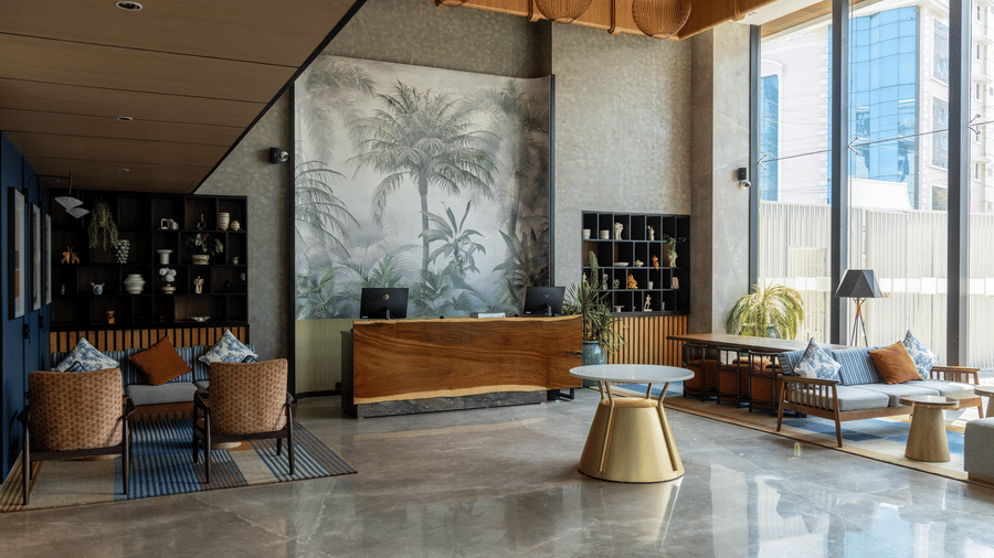 Stylish main lobby featuring 1 wooden reception desk and a tropical wall mural at Sands Point Hotel, Pondicherry.
