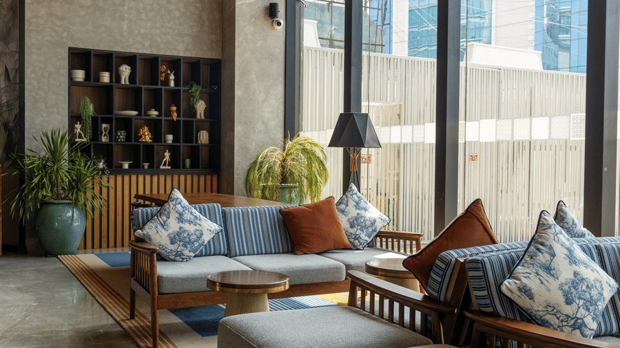 Comfortable indoor seating with 2 large potted plants and wooden furniture at Sands Point Hotel, Pondicherry.