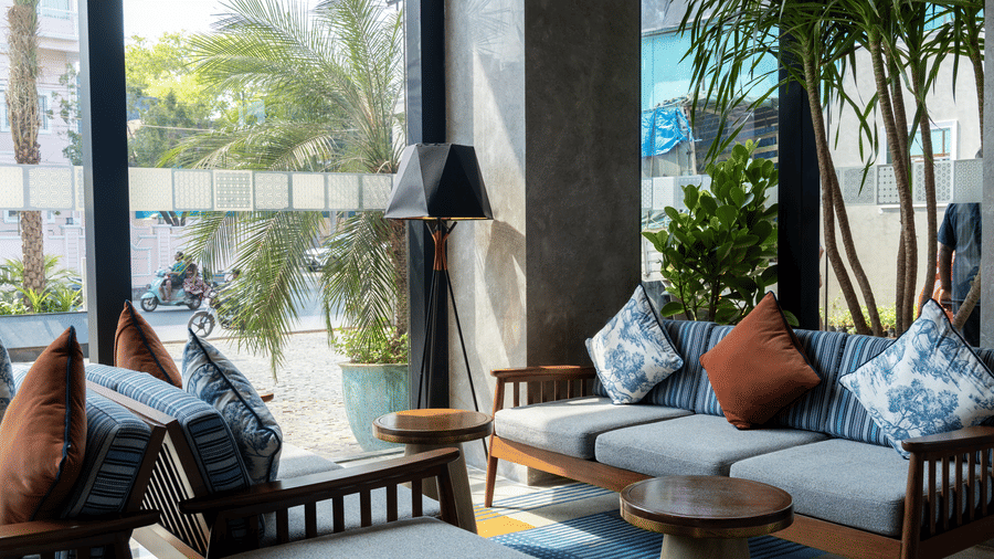 A bright lounge area with 1 blue sofa and decorative cushions at Sands Point Hotel, Pondicherry.