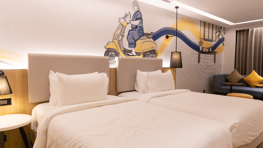 A Premium Twin Room at Sands Point Hotel, Pondicherry, featuring 2 beds with white linen and light grey headboards with reading lamps.