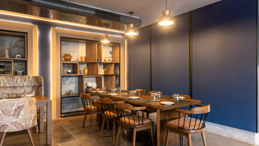 An intimate dining space with 1 wooden table and a dark blue feature wall at Sands Point Hotel, Pondicherry.