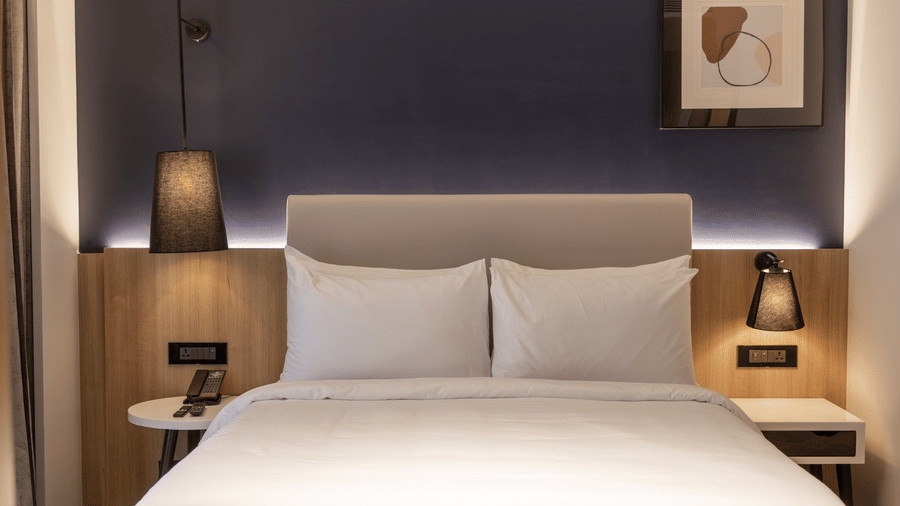 A Standard Room at Sands Point Hotel, Pondicherry, featuring a king bed with black swing arm reading lamps.