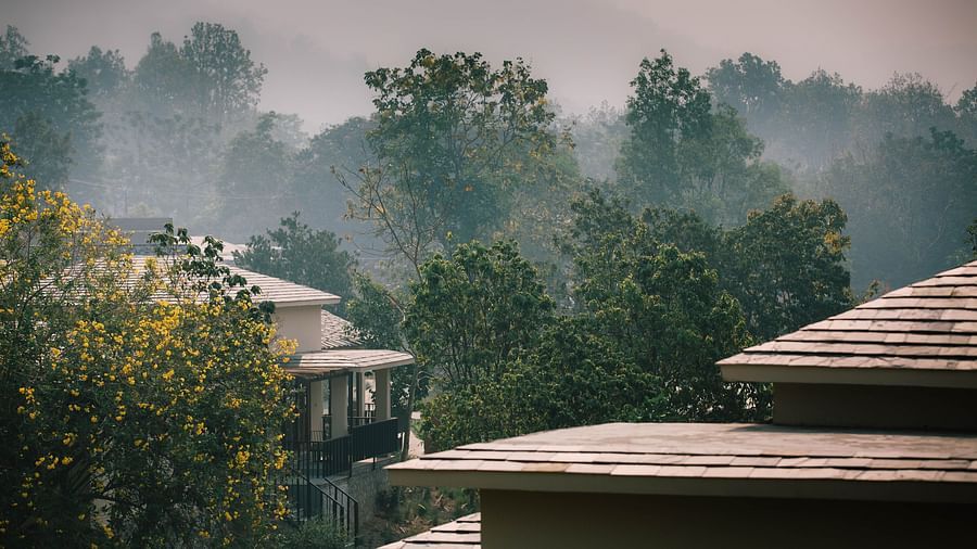 Aerial view of the villas at Saraca Resort & Spa Corbett with the mountains of Uttarakhand in the backdrop on a foggy day