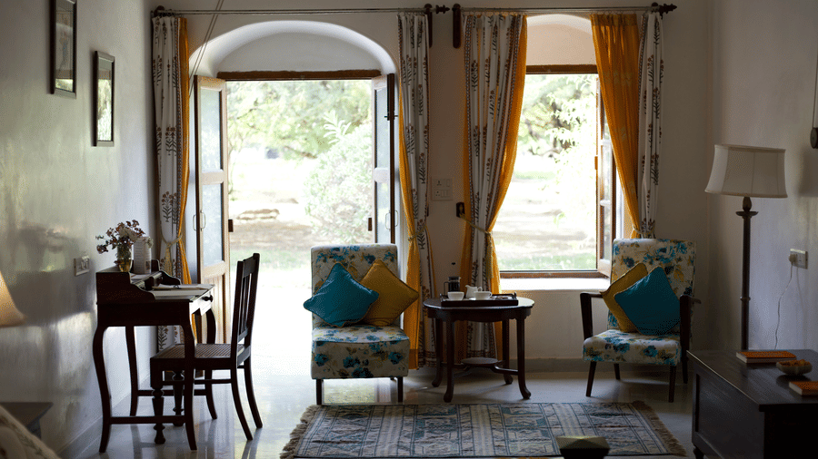 Spacious heritage room with seating area, large windows and garden views at Shahpura Bagh.