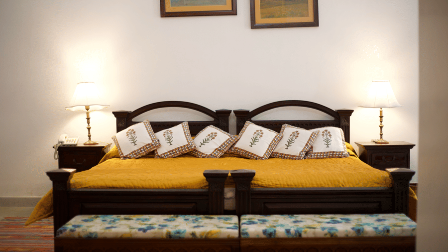 Comfortable king size bed with classic décor and warm lighting in a heritage room at Shahpura Bagh.