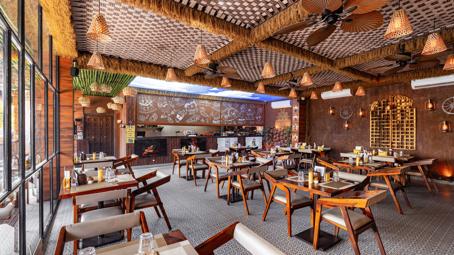 Full view of an empty, modern dining hall with a striking blue sky and clouds mural on the ceiling.