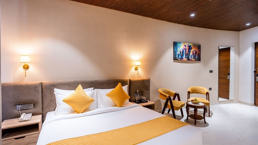 A large bed, a night stand, two comfortable chairs in our river view room - Shervani Pebbles & Pines, Corbett