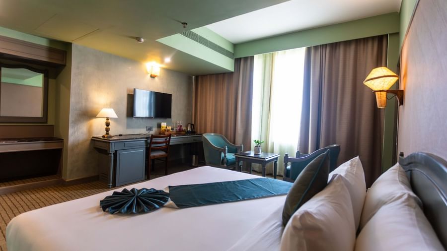  A guest room at Shilton International, Kochi, with a bed, TV, work desk, and seating area.