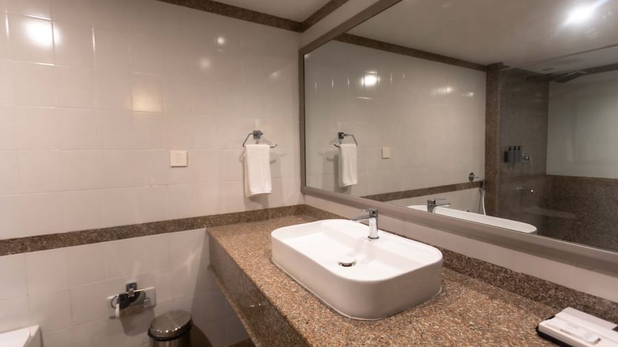 A contemporary bathroom at Shilton International, Kochi with a vanity, modern sink, and a large mirror.