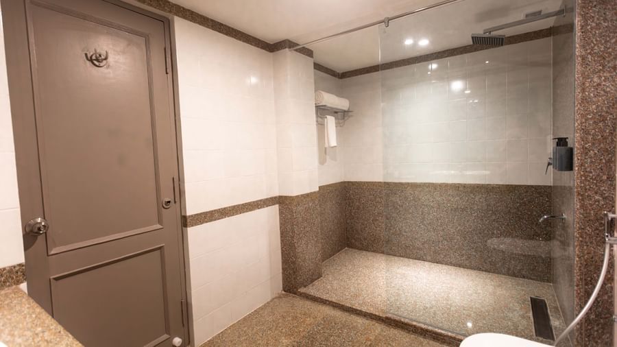 A shower area at Shilton International, Kochi, with a glass enclosure and a private toilet room.