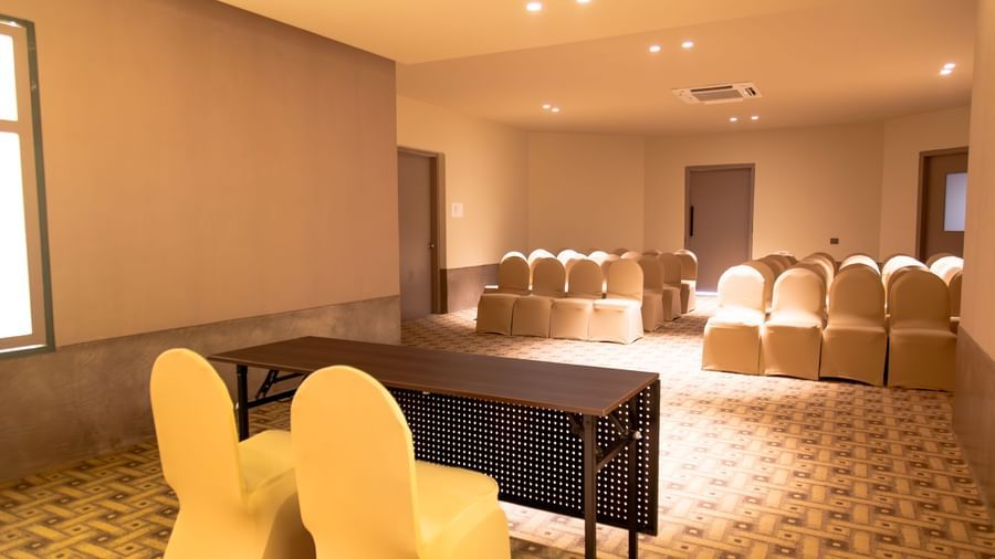  A well-lit conference room at Shilton International, Kochi, with rows of chairs set up for an event, and two tables in front.