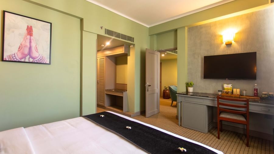  A guest room at Shilton International, Kochi, with a bed, a desk area, and an open wardrobe.