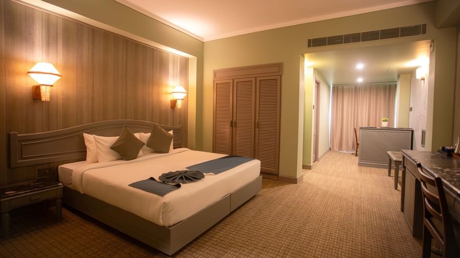  A spacious guest room at Shilton International, Kochi, with a bed, a desk area, and an adjoining room.