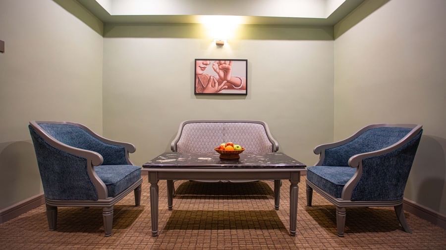 A stylish seating area at Shilton International, Kochi, with two armchairs, a sofa, and a coffee table.