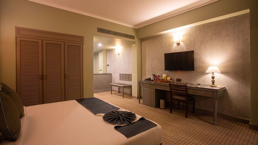 A guest room at Shilton International, Kochi, with a bed, a desk area, and a separate seating area.