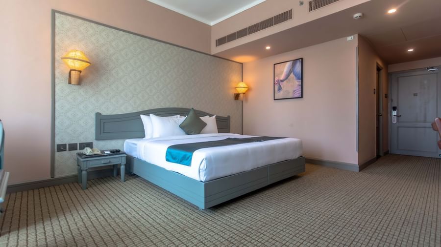  A guest room at Shilton International, Kochi, with a large bed, wall-mounted television, and stylish decor.
