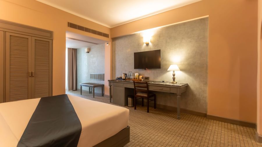 A guest room at Shilton International, Kochi, with a bed, a desk, and a television.