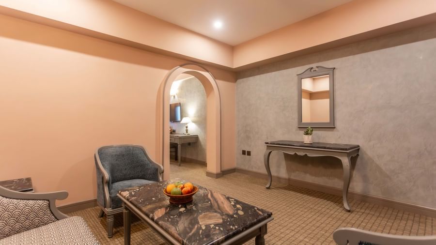  A lounge area at Shilton International, Kochi, with comfortable seating and an arched doorway leading to another room.