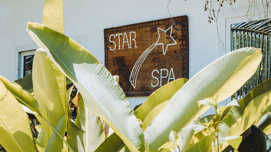 A serene outdoor setting with green foliage and a signboard at Shooting Star Spa