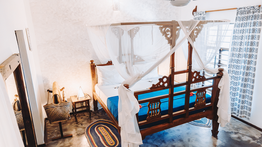 View of a bed, bed side table, ceiling fan and air-conditioner in the background - Shooting Star Boutique Hotel.