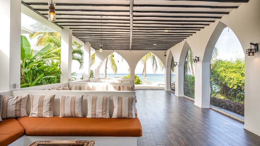 Corner lounge with soft cushions, wooden floors, and arched windows opening to lush greenery - Shooting Star Boutique Hotel.