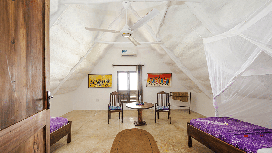 A cosy room with a wooden bed and a table with chairs with windows in the background offering natural light in Sea View Family Cottages - Shooting Star Boutique Hotel.