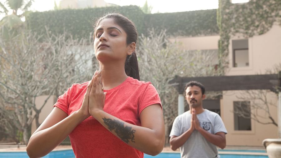 People doing yoga poses outdoors, sunlight, trees in background - Shreyas Retreat
