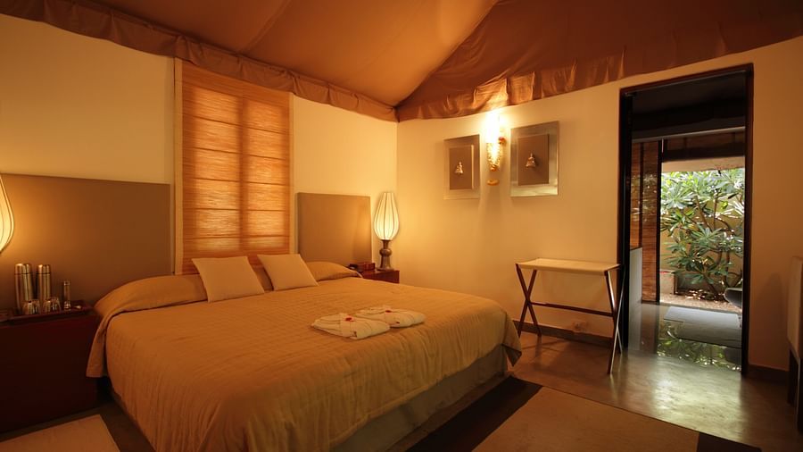 A bedroom with a bed, lamps, and a view of a garden - Shreyas Retreat